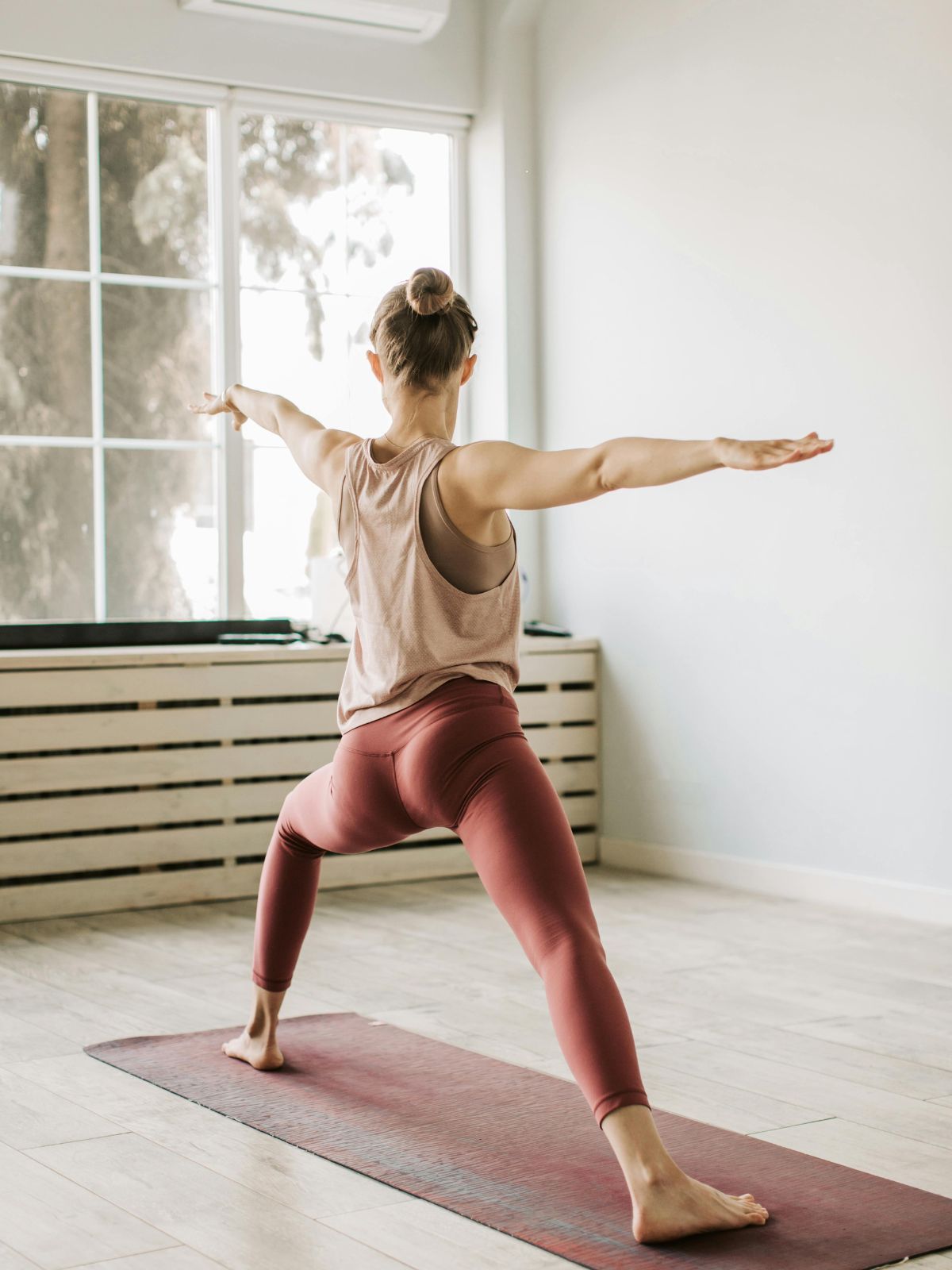Frau in Yoga-Pose am Fenster